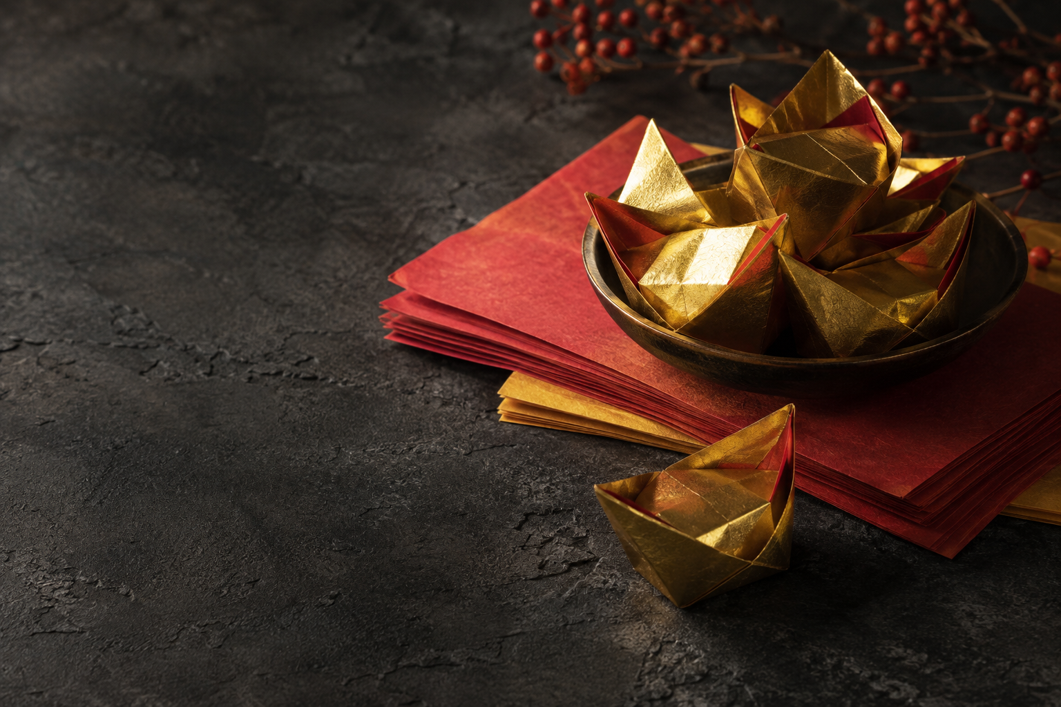 Illustrative still life of folded gold ritual paper and vermilion paper on dark stone